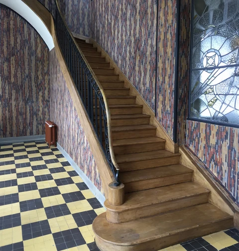 Escalier courbe en bois avec rampe métallique noire dans hall d'entrée élégant