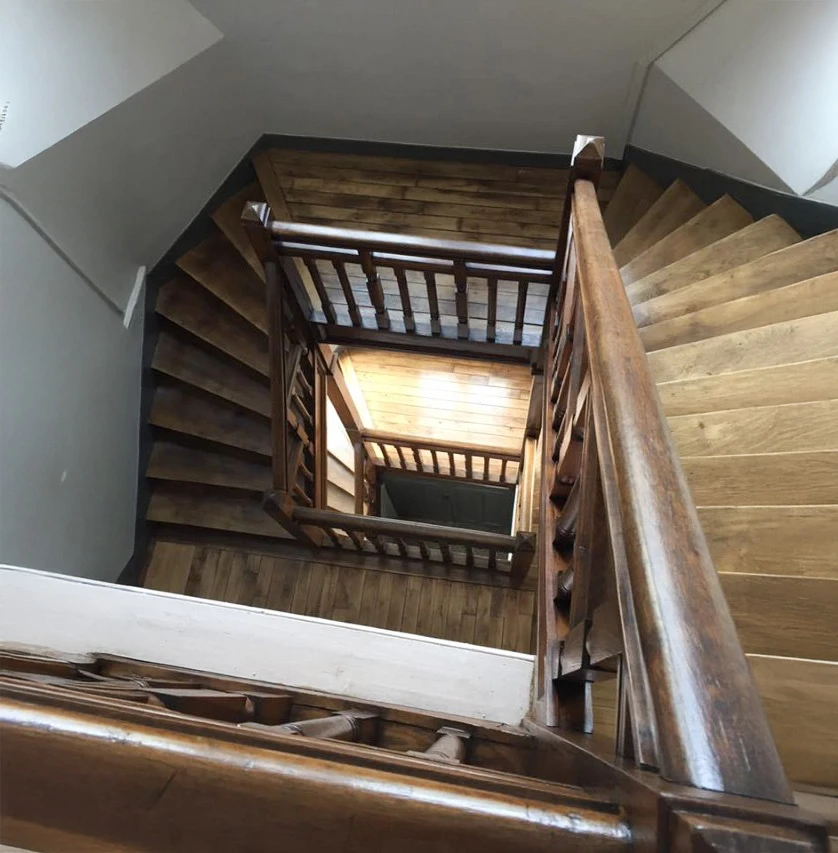 Escalier en bois massif à rampe tournante dans cage d'escalier intérieure