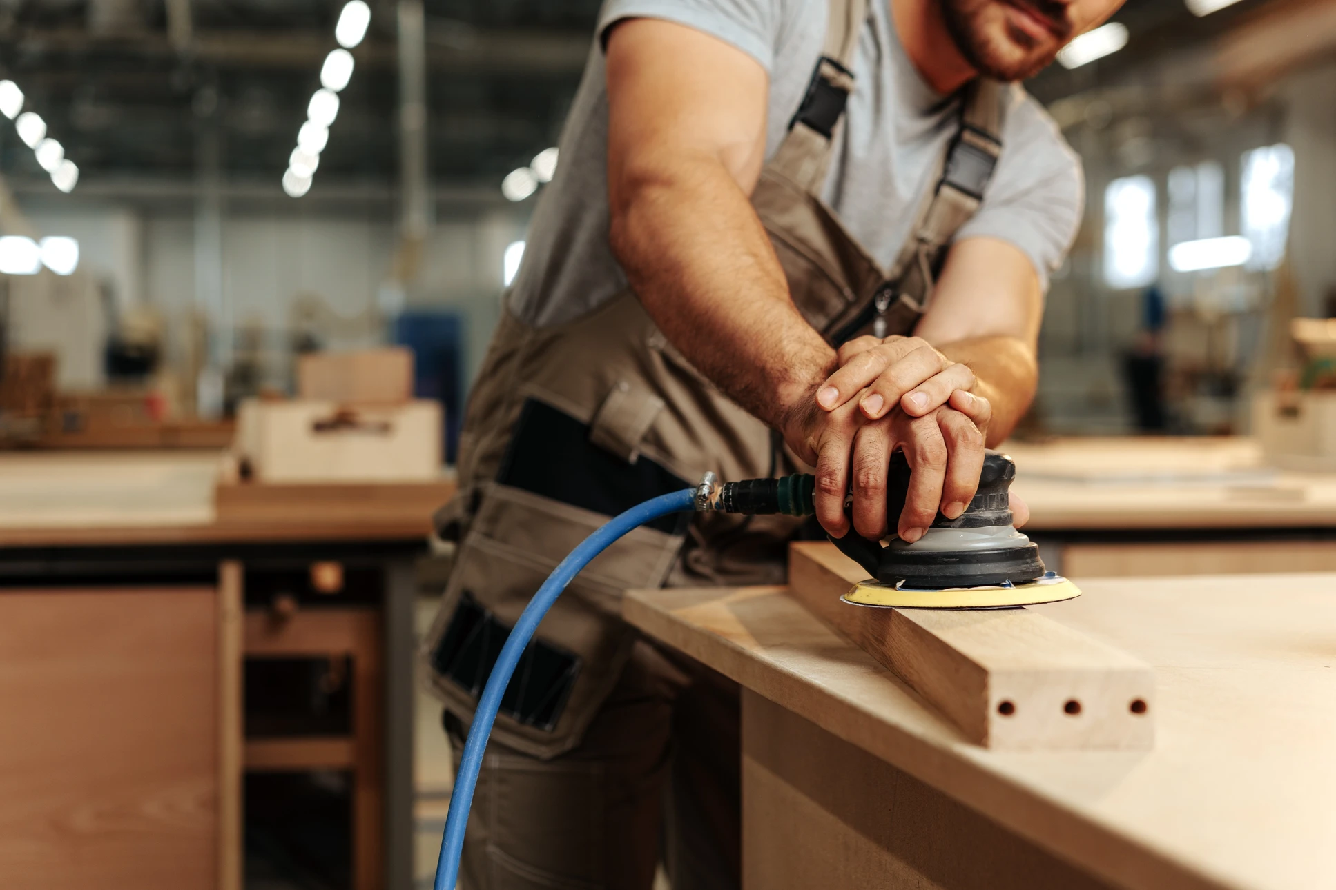 Artisan utilisant un rabot &agrave; main sur une planche de bois dans un atelier ext&eacute;rieur