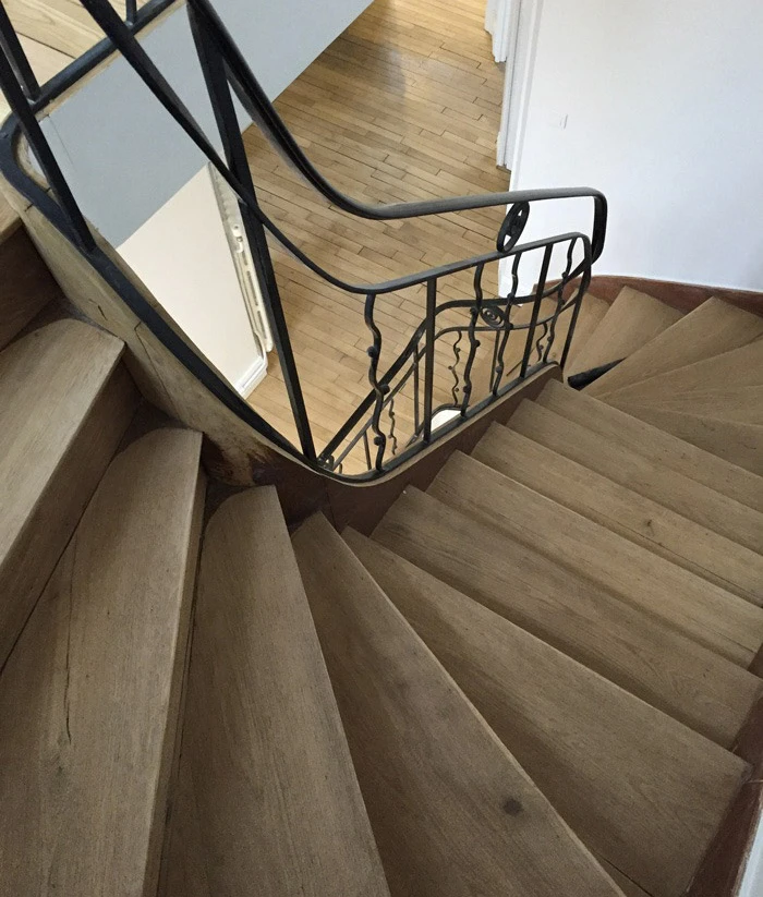 Escalier moderne suspendu en bois exotique avec garde-corps métallique à barreaux horizontaux dans hall d'entrée contemporain